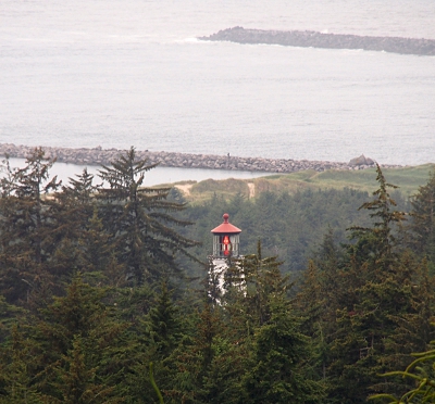 [This inland lighthouse is just visible among the trees inland of it. The red light in the tower is lit. Several jetties are seen in the bay.]